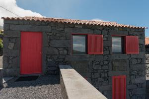Terra AltaCasa do Sanguinho - Estúdio, Quinta do Rochão的一座石屋,设有红色的门窗