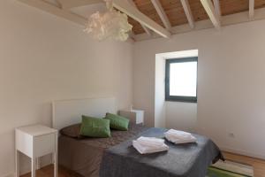Terra AltaCasa do Sanguinho - Estúdio, Quinta do Rochão的一间卧室配有一张带绿色枕头的床和一扇窗户