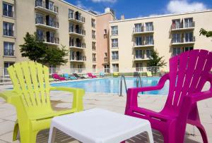 蒙泰夫兰杜帕尔克瓦尔欧洲公寓式酒店的游泳池前的三把五彩缤纷的椅子和一张桌子