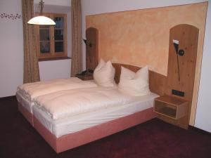 希格斯多夫阿尔特帕斯特酒店的一间卧室配有一张大床和木制床头板