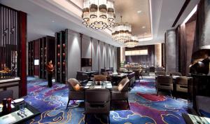呼和浩特呼和浩特富力万达文华酒店的餐厅铺有色彩缤纷的地毯,配有桌椅