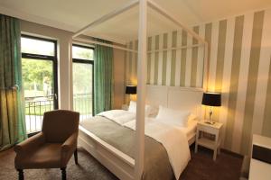 克里维茨巴斯歇斯特城堡酒店的一间卧室配有一张天蓬床和一把椅子