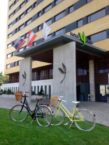 科希策优思明科希策酒店 的两辆自行车停在大楼前的草地上
