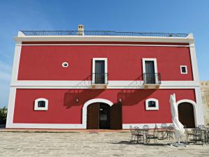 利扎诺Masseria San Vito - Agriturismo的一座红色的建筑,前面设有桌椅