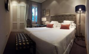 苏马拉加艾克斯百里酒店的一间卧室配有一张大床,配有白色床单和红色枕头