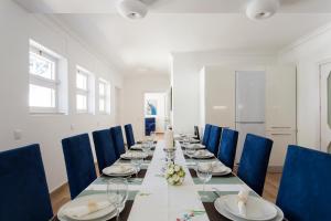 塞辛布拉Villa Branca do Castelo的长长的用餐室配有长桌子和蓝色的椅子