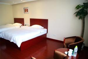 郑州格林豪泰郑州二七区万达地铁站商务酒店的一间卧室配有两张床、一张桌子和一把椅子