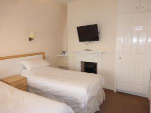 伦敦马普尔住宿加早餐旅馆的一间卧室设有两张床,墙上配有电视。