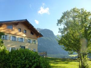 阿布特瑙Ferienwohnung Bauernhaus Untermoas的一座田野上的建筑,旁边有一棵树