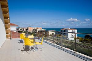 托雷梅利莎哥奇奈拉住宅酒店的阳台设有黄色椅子和桌子,享有海景。