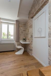 特罗吉尔Bifora Heritage Hotel的一间设有石墙和白色椅子的房间