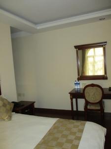 阿克苏姆Sabean International Hotel的一间卧室配有一张床、一张桌子和一个窗户。
