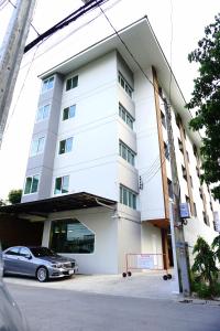 曼谷阿尼素坤逸101公寓的前面有一辆汽车停放的白色建筑