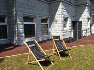 格丁尼亚Panorama Gdynia Rooms的两把椅子坐在房子前面的草上