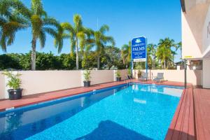 凯恩斯凯恩斯市棕榈汽车旅馆的一座带有读取大使馆棕榈树标志的酒店游泳池
