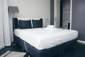 阿姆斯特丹运河住宿加早餐旅馆的一张配有白色床单和黑色枕头的大床