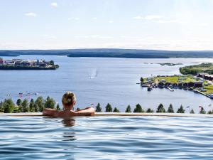 皮特奥KUST Hotell & SPA的女人在无边游泳池俯瞰湖泊
