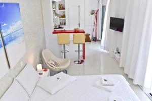 圣马太奥斯Mavres Luxury Studio的白色卧室配有白色的床和红色的柜台
