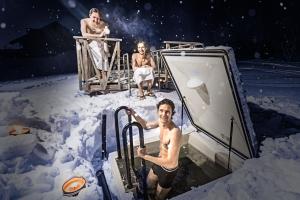 基尔匹斯扎我维屯德拉度假酒店的三人站在甲板上,站在雪上