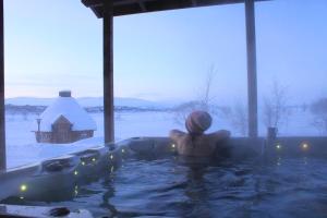 基尔匹斯扎我维屯德拉度假酒店的坐在一个雪覆盖的院子的热水浴缸中的人
