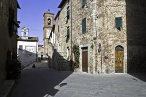 Civitella MarittimaLa Casina di Neda的一条小巷,拥有一座带钟楼的大型石头建筑