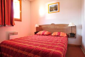 土绪尔Résidence Goélia Les Chalets de la Toussuire的一间卧室配有红色的床和两个枕头