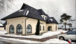 Ķegums奧斯克洛斯酒店的雪中带黑色屋顶的白色房子