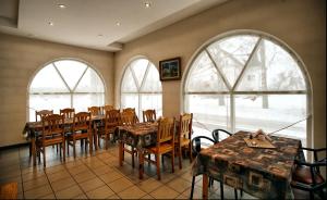 Ķegums奧斯克洛斯酒店的用餐室设有桌椅和窗户。