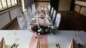 伦布尔克Pension Dymník的一张长桌子,上面有白色的椅子和鲜花