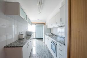 马托西纽什波尔图河海码头公寓的厨房配有白色橱柜和花岗岩台面