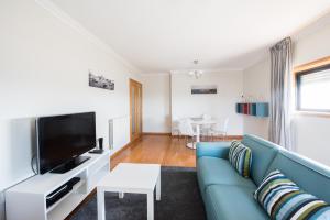 马托西纽什波尔图河海码头公寓的客厅配有蓝色的沙发和电视