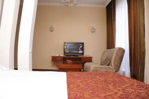 塔拉兹ABAI INN - Nursaya的酒店客房带一张床、一台电视和一把椅子