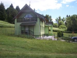 BukovinaApartmány Smrečie的绿色房子,在田野顶部设有阳台