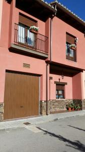 阿尔巴拉辛Casa Rural Claudia的粉红色的房子,设有车库和2个窗户