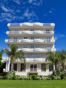 阿尔巴·阿德里亚蒂卡奥林巴斯度假酒店的一座高大的白色建筑,前面有树木
