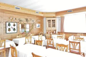 利维尼奥加尼阿尔普兰酒店的用餐室配有白色的桌子和木椅