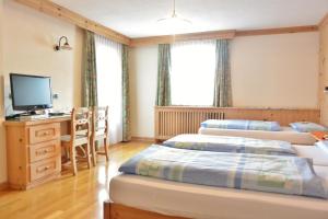利维尼奥加尼阿尔普兰酒店的客房设有三张床、一张桌子和一台电视。