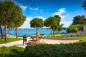 罗维尼Maistra Select Island Hotel Istra的公园喷泉旁的两个人