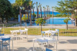 希贝尼克Amadria Park Beach Hotel Jure的一组桌子和椅子,背景是海洋