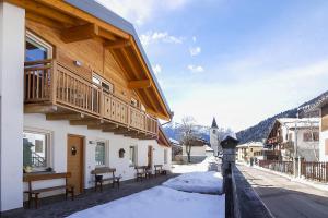 摩德纳迪-坎皮格里奥Dolomiti di Brenta House 2的一座位于雪 ⁇ 街道上的木结构建筑,设有阳台