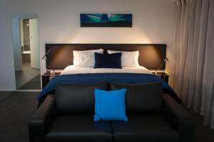 但尼丁欧罗拉乔治酒店的一间卧室配有一张床和一张带蓝色枕头的沙发