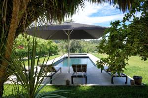 法菲卡萨多西姆乡林民宿的一个带遮阳伞和两把椅子及一张桌子的游泳池