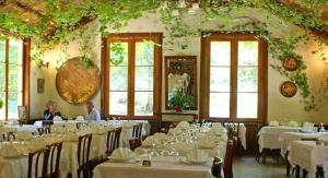 维扎沃纳蒙蒂欧罗酒店的一间设有白色桌椅和窗户的用餐室