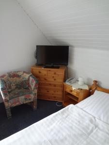 耶弗尔Hotel-Pension Stöber的一间卧室配有一张床、一台电视和一把椅子