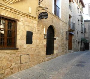 阿尔克萨尔卡萨雅柏内罗旅舍的街道上一座石头建筑,有一道黑色的门