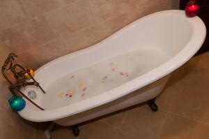 TrăisteniConacul Dascalu的浴室内设有一个装饰的白色浴缸