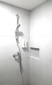 安吉利斯950公寓的浴室铺有白色瓷砖,设有淋浴。