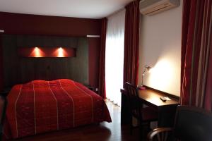皮蒂维耶斯卡拉酒店的一间卧室配有红色的床、一张书桌和一个窗户。
