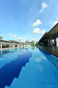 新加坡乌节路大臣酒店的一座大型游泳池,位于一座建筑的一侧,铺有蓝色瓷砖