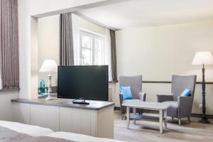 腓特烈Hotel Klein Amsterdam的酒店客房带电视和椅子